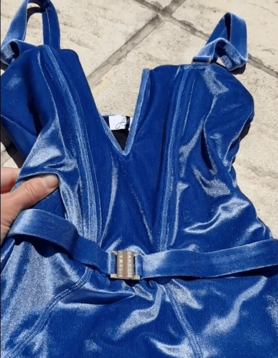 A woman talking about the vibrant and elegant blue velvet swimsuit as it shimmers under the light, showcasing its luminous color and luxurious textureut