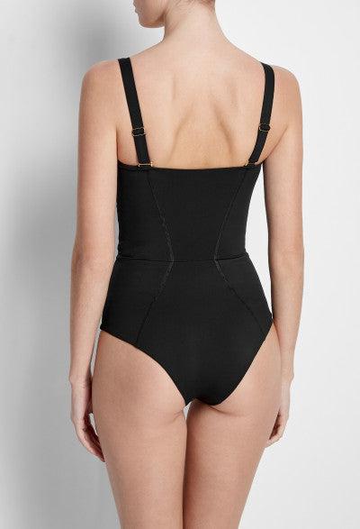 Model posing from the back in a Sama Danesh black one piece swimsuit with black straps, showing off an hourglass and flattering fit